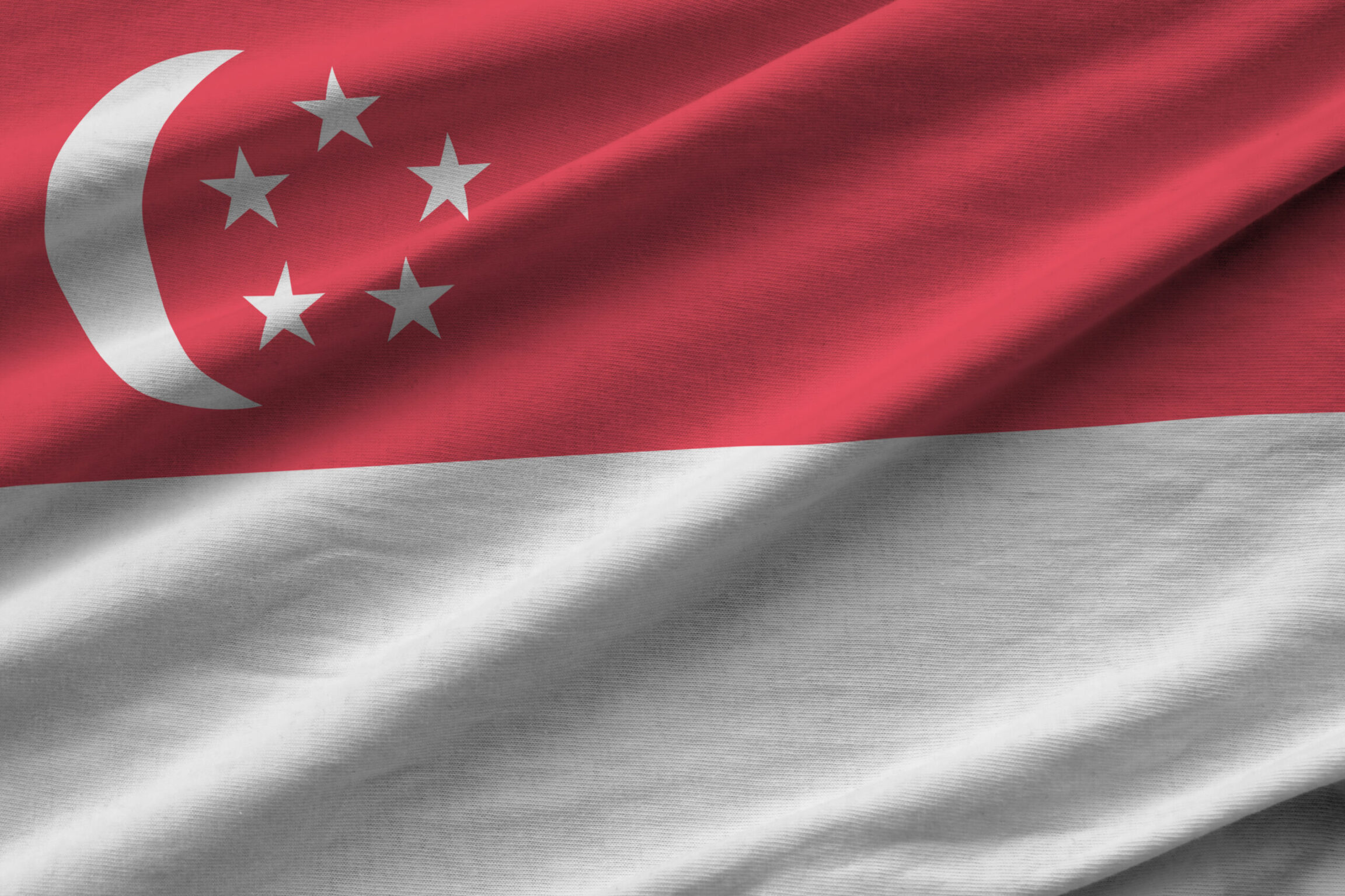 Singapore flag with big folds waving close up under the studio light indoors. The official symbols and colors in fabric banner
